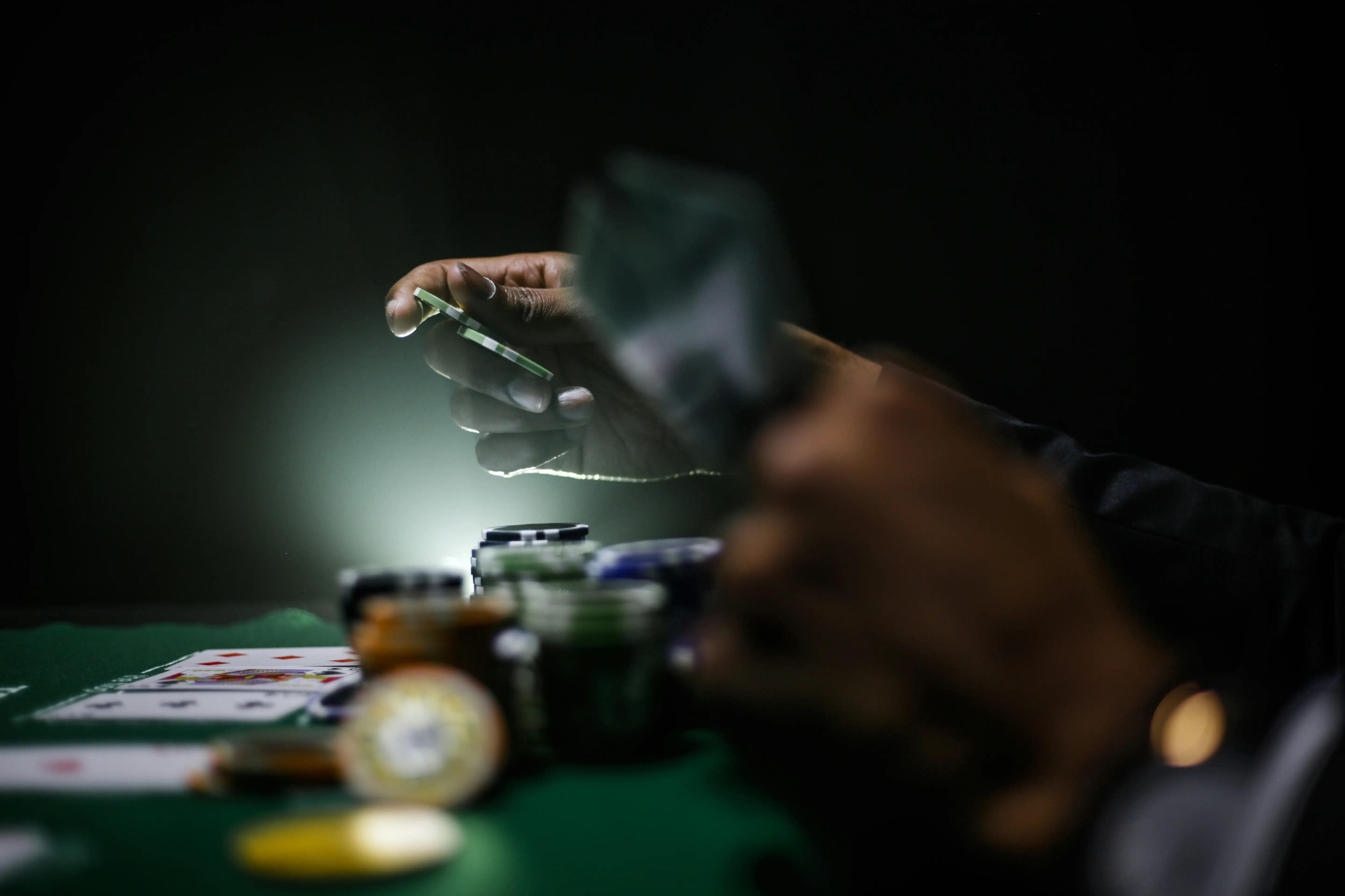 Hånd over spillekort og kasinosjetonger ved et pokerbord